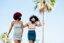 Zwei lateinamerikanische Frauen mit Afrohaaren, die Gesichtsmasken tragen — Stockfoto