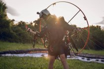 Young man, with the Powered Paragliding engine in his shoulders, gets ready to fly at sunset. — Stock Photo