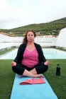 Женщина практикует йогу на террасе дома, осанка лотоса — стоковое фото