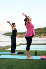 Zwei Frauen praktizieren Yoga auf der Terrasse des Open-Air-Hauses — Stockfoto