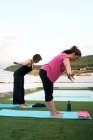 Zwei Frauen praktizieren Yoga auf der Terrasse des Open-Air-Hauses — Stockfoto