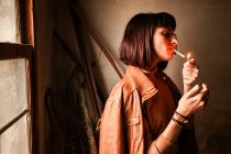 Портрет дівчини-брюнетки, що запалює цигарку — стокове фото