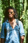 Musician walking with the guitar hanging on his back. He is walking in a park with vegetation. — Stock Photo