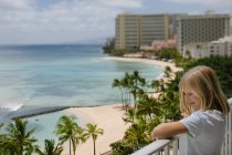 Menina sorridente goza de Waikiki vista para o mar a partir da varanda do hotel (tilt shift) — Fotografia de Stock