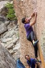 Sportlicher Mann klettert mit männlichem Spotter auf Felsbrocken — Stockfoto