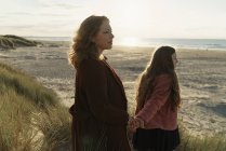 Madre e figlia in piedi sulla spiaggia contro vista sul mare — Foto stock