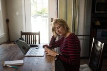 Розчарована жінка сидить на кухні перед кавою в лаптопі — стокове фото