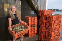 Agricultora de moluscos fêmea segurando caixa de ostras — Fotografia de Stock