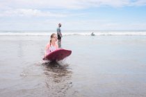 Chica joven vistiendo googles sosteniendo boogie board en la playa - foto de stock