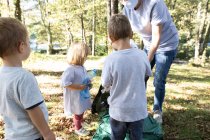 Mother collecting plastic bottles with her children in the forest — Stock Photo