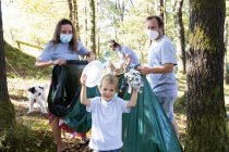 Familias recogiendo basura en un bosque. Concepto de reciclaje - foto de stock