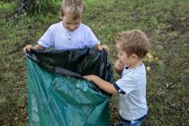 Crianças voluntárias segurando um saco de lixo em um parque natural. — Fotografia de Stock