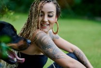 Giovane donna con capelli biondi intrecciati colorati abbracciando il suo cane — Foto stock