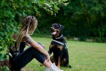 Молодая женщина с белокурыми косичками обнимает свою собаку — стоковое фото