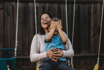 Мальчик с счастливой мамой на качелях — стоковое фото