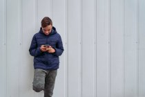 Teen with mobile phone on a white wall — Stock Photo