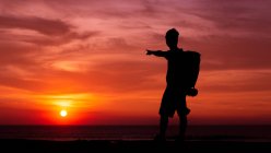Чоловік на заході сонця після допомоги дитині черепахи йдуть в океан — стокове фото