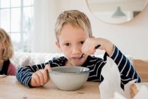 Young boy eating breakfast at home before school — Stock Photo