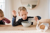 Niño durante la leche en su desayuno en casa antes de la escuela - foto de stock