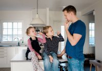 Padre enseñando a sus hijos a cepillarse los dientes antes de la escuela - foto de stock
