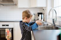 Junge hilft beim Abwasch nach dem Frühstück vor der Schule — Stockfoto