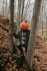 Uomo che indossa spaventosa testa di zucca intagliata nel bosco per Halloween. — Foto stock