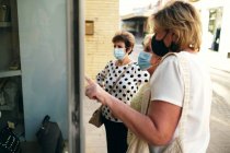 Reife Frauen blicken auf ein Fenster und zeigen auf die Tasche — Stockfoto