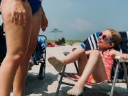 Una bambina sorride ad una donna sulla spiaggia. — Foto stock