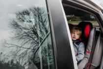 Маленький хлопчик сидить у машині з відчиненими дверима . — стокове фото