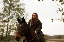 Young horsewoman with a horse outside riding — Stock Photo