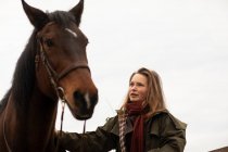 Giovane cavallerizza con un cavallo fuori — Foto stock