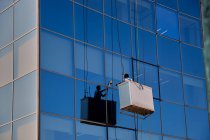 Operaio che pulisce le finestre in un moderno edificio di vetro, Pamplona Spagna — Foto stock