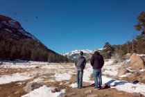 Dois homens observando pássaros nas montanhas rochosas em um dia ensolarado — Fotografia de Stock