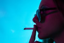 Portrait girl with neon lights smoking — Stock Photo