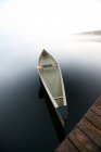 Un'elegante canoa legata a un molo su un tranquillo stagno nel Maine. — Foto stock