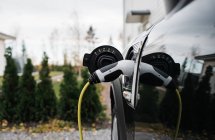 Plomo del coche eléctrico enchufado en un coche eléctrico en casa - foto de stock