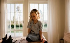 Giovane ragazza seduto disegno a casa con la penna sul viso — Foto stock