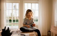 Молодая девушка рисует на руке и лице дома — стоковое фото