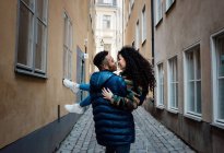 Homme portant sa petite amie dans les rues de l'Europe regardant dans l'amour — Photo de stock