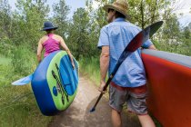 A young couple carry standup paddleboards to the water in Oregon. — Stock Photo