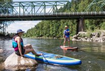 A young couple enjoy the river on their SUPs in Oregon. — Stock Photo