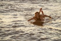 Athletic female paddles on surf board at sunset in hawaii — Stock Photo