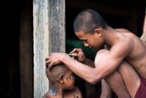 Молодой монах бреет волосы на голове послушника с бритвой, недалеко от Сипау, Мьянма — стоковое фото
