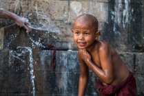 Monje sin camisa novato bañándose bajo agua corriente al aire libre, cerca de Hsipaw, Myanmar - foto de stock