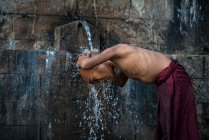 Novizio monaco senza camicia fare il bagno sotto l'acqua corrente all'aperto, vicino a Hsipaw, Myanmar — Foto stock