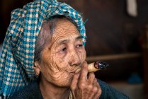Senior Birmano mujer fumar grueso Birmano paja cigarro, Bagan, Myanmar - foto de stock