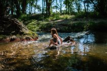 Молодая счастливая девушка играет в реке в солнечный летний день — стоковое фото