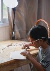 Una chica cortando una cuerda en su trabajo artesanal - foto de stock