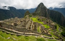 Machu picchu view with green grass and walking people — Stock Photo