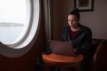Uma mulher que trabalha remotamente na cabine de um navio de cruzeiro. — Fotografia de Stock